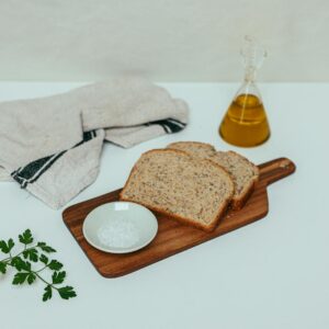 Delicious whole grain bread served with olive oil, salt, and parsley on a chopping board.